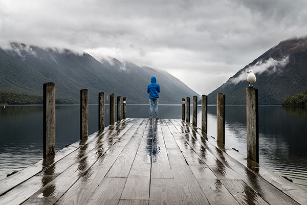 Person-on-pier-looking-at-misty-mountain